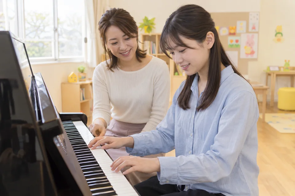 先生と一緒にピアノの鍵盤に触れる授業イメージ
